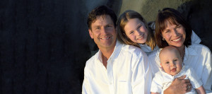 Happy family together: Dad, young daughter, mom, and little baby, all wearing white